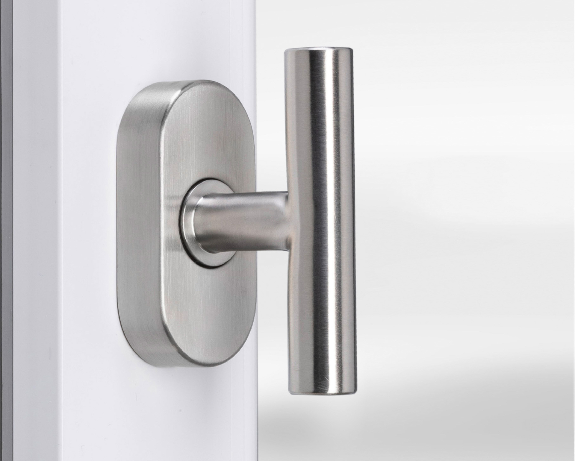 Eurolaton | Eine Nahaufnahme eines modernen, metallischen Türgriffs mit gebürsteter Oberfläche, der an einer weißen Tür angebracht ist und an das elegante Design der „Fenstergriffe Edelstahl“ erinnert. Der Griff weist ein horizontales, zylindrisches Design auf und ist auf einer ovalen Montageplatte befestigt.