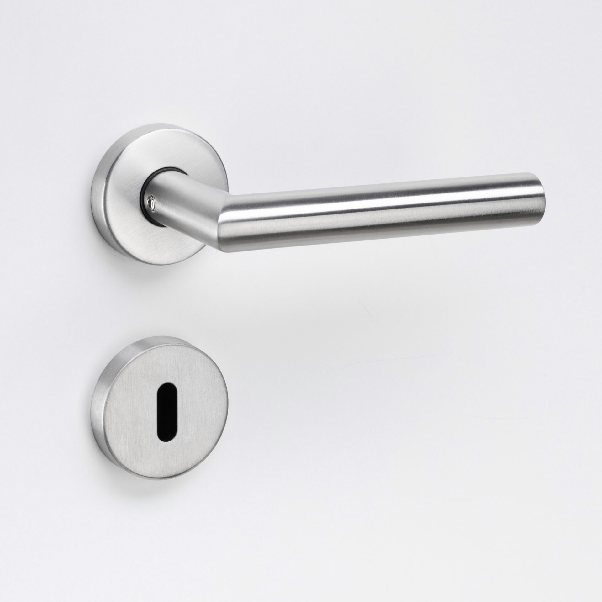 Eurolaton | Eine Nahaufnahme einer modernen Türklinke aus gebürstetem Metall und einer dazu passenden Schlüssellochblende aus unserem Türbeschläge-Sortiment, montiert an einer weißen Tür.